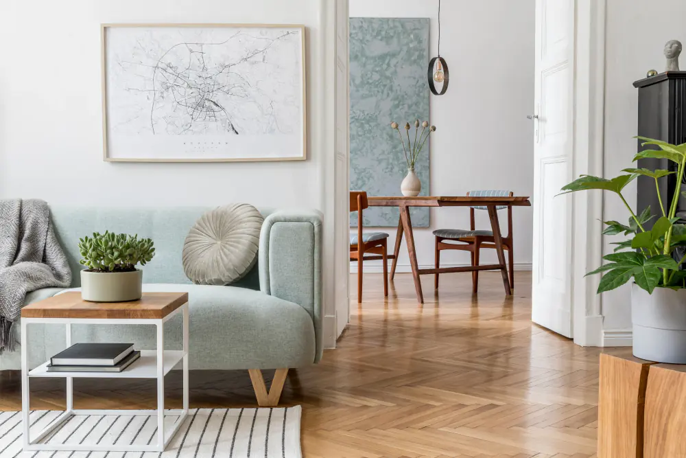Bright living room with a sage sofa, wood dining set, and herringbone floors