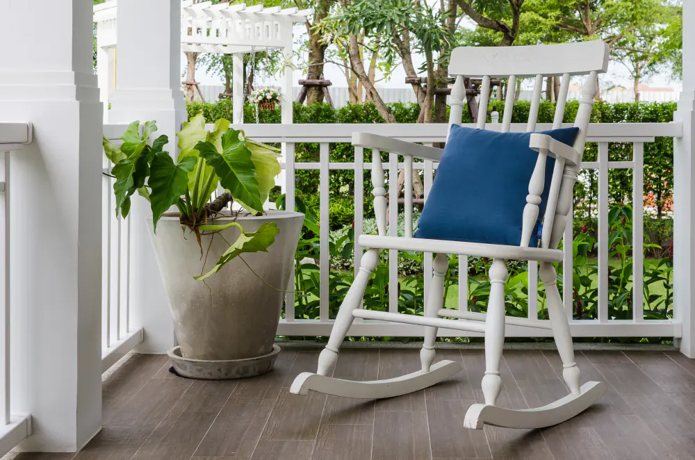 White rocking chair with a navy cushion on a covered front porch